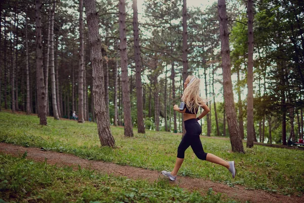 Una mujer deportiva corre por el bosque . — Foto de Stock