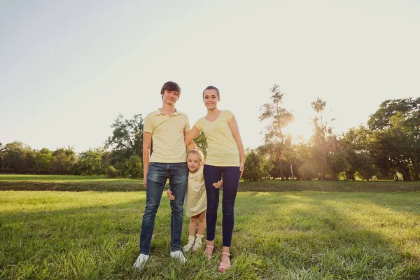 Los padres con el niño de pie sobre la hierba en el parque . — Foto de Stock