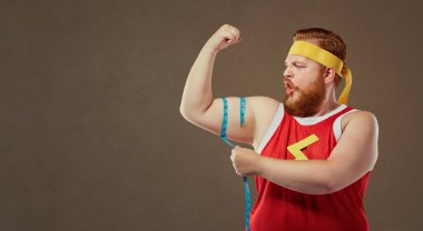 Spor giyim komik şişko bir adam kolunu bir centim ile ölçer