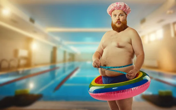Толстый смешной человек в надувном круге в бассейне — стоковое фото