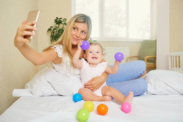 Mamma gör ett foto på telefonen med barnet i rummet. Salfie — Stockfoto