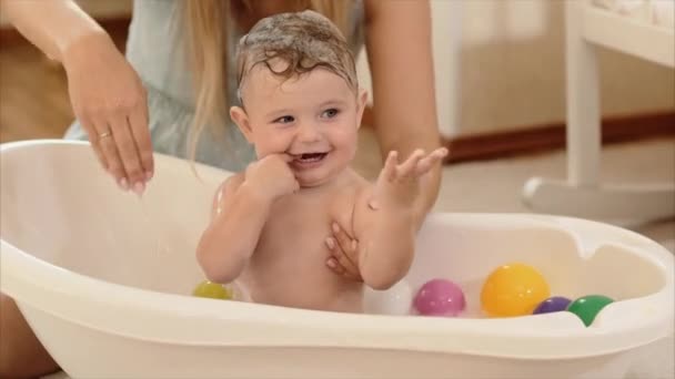 Мать купает ребенка в ванной комнате в комнате — стоковое видео