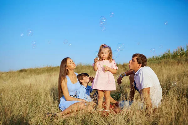 A happy family on the nature blowing soap bubbles. — Stock Photo, Image