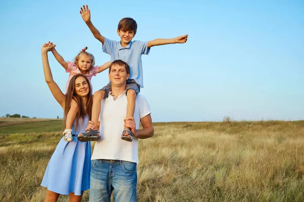 Happy family in nature smiling with their hands up. — Stock Photo, Image