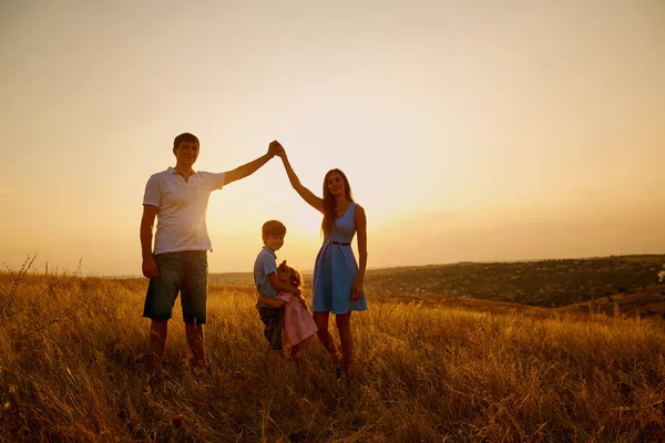 In het veld bij zonsondergang en gelukkige familie. — Stockfoto