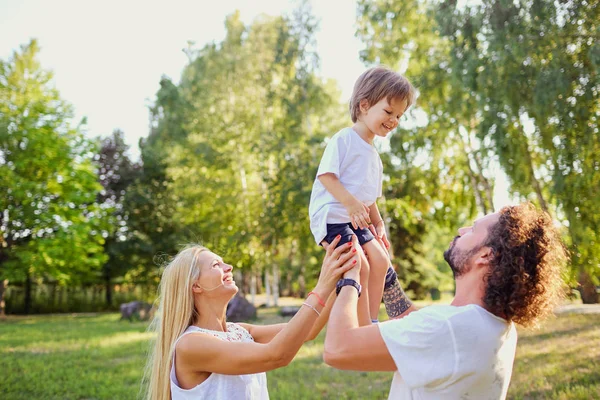 Glückliche Familie spielt mit einem Kind im Park. — Stockfoto