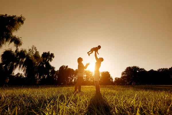 Happy family playing with a child at sunset in the park. — Stock Photo, Image