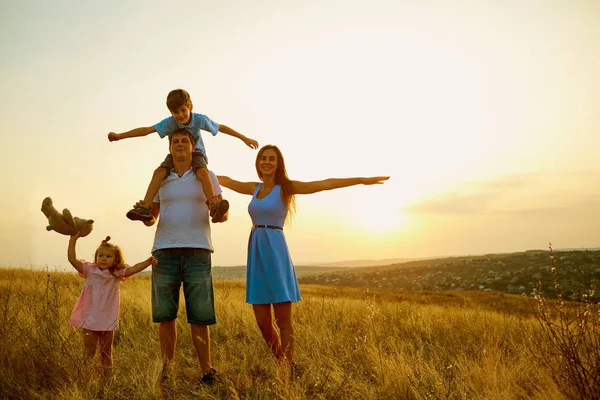 Lycklig familj i fältet vid solnedgången på sommaren. — Stockfoto