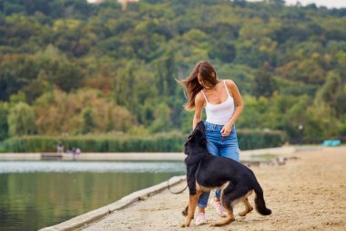 Bir kız köpeğini yaz sahilde parkta ile oynuyor.
