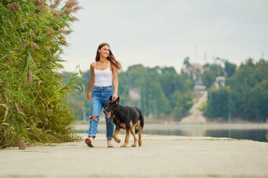 Genç bir kız ile bir köpek parkta yürüyüş.