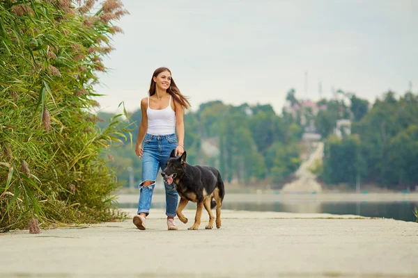 Genç bir kız ile bir köpek parkta yürüyüş.