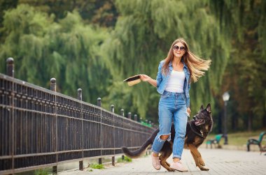 Genç bir kız ile bir köpek parkta yürüyüş.