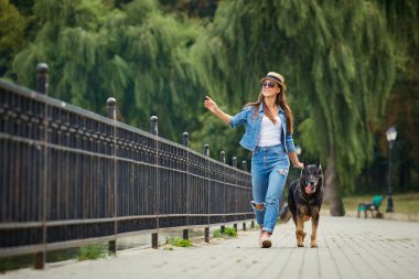 Genç bir kız ile bir köpek parkta yürüyüş.