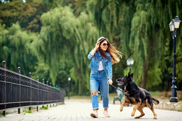Genç bir kız ile bir köpek parkta yürüyüş.