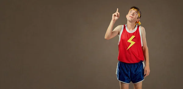 Un tip subțire amuzant în haine sportive își arată degetul în sus . — Fotografie, imagine de stoc