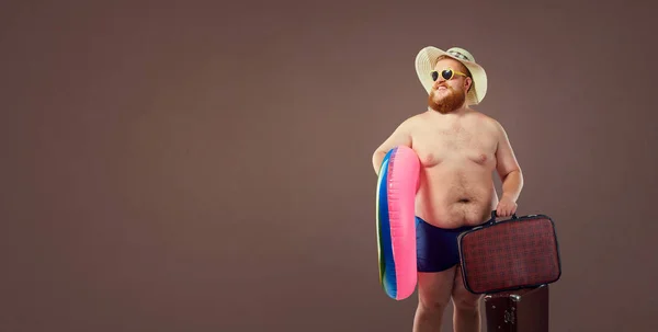 Смешной жирный бородатый мужчина с чемоданом в шляпе и очками на ва — стоковое фото