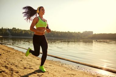 Bir genç kadın atlet parkında bir parkta günbatımında çalışır.