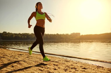 Gölde bir parkta günbatımında bir genç kadın atlet çalışır.