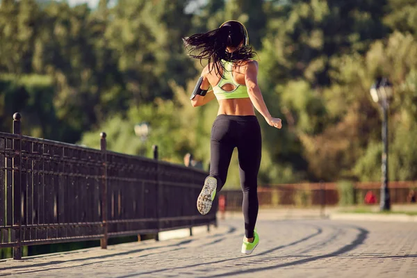 Uma mulher corredora morena corre no parque correndo . — Fotografia de Stock