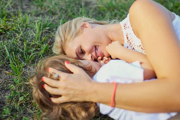 Madre e hijo están jugando abrazos en la hierba en el parque . —  Fotos de Stock