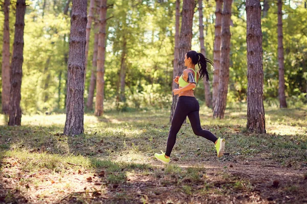 Esportes menina morena corre através da floresta . — Fotografia de Stock