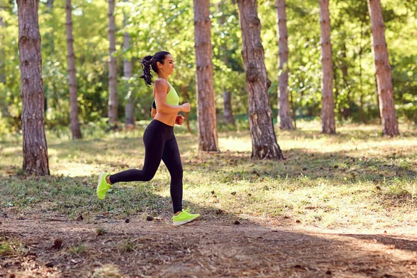 Sportovní holka brunetka vede lesem. — Stock fotografie