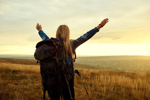 Una chica viajera con una mochila levantó las manos . — Foto de Stock