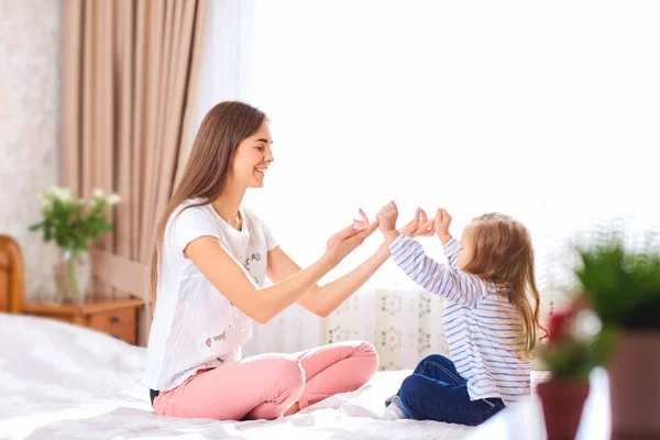 Mutter und Tochter auf dem Bett am Fenster. — Stockfoto