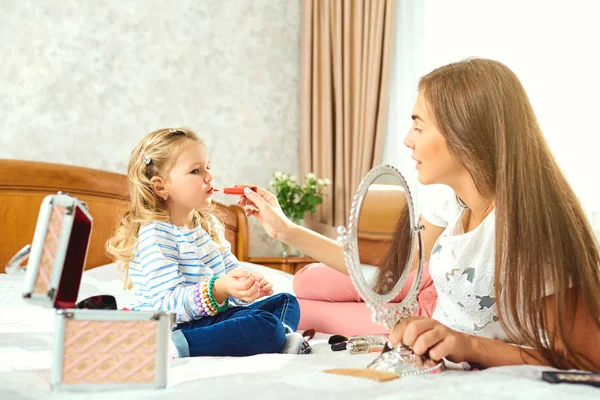 Anne ve kızı makyaj yapmak, pencerenin yanındaki yatakta oyun.