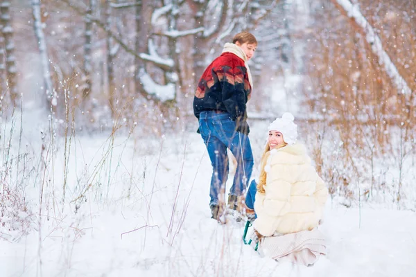 Szczęśliwa para jest jazda na sankach w śniegu w parku w win — Zdjęcie stockowe