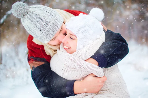 Молодая пара обнимается на снегу в зимнем парке — стоковое фото