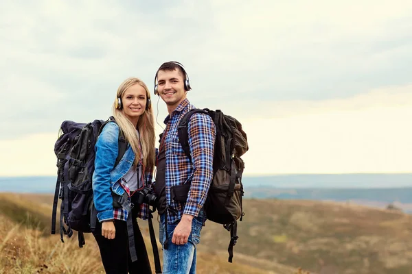 Casal feliz de turistas em fones de ouvido na natureza — Fotografia de Stock