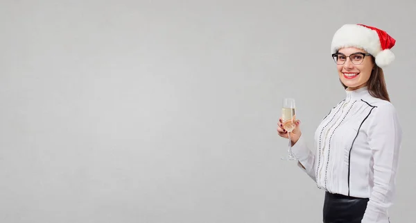 Uma menina de chapéu de Pai Natal com uma taça de champanhe na mão para — Fotografia de Stock
