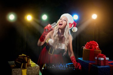 Noel Baba şapkalı DJ kız mikrofona Noel gününde söylüyor..