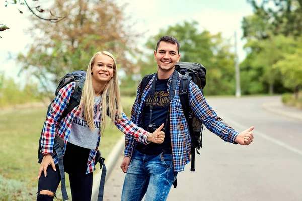 Bir çift otostopçu durmak üstünde belgili tanımlık yol