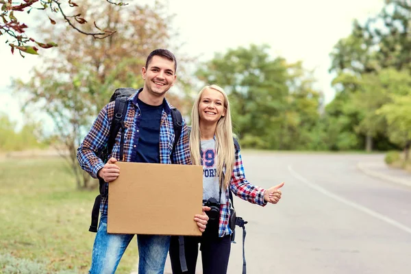 Bir çift otostopçu durmak üstünde belgili tanımlık yol