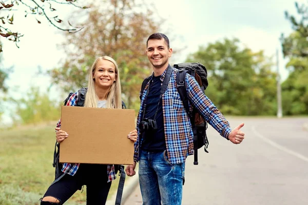 Bir çift otostopçu durmak üstünde belgili tanımlık yol
