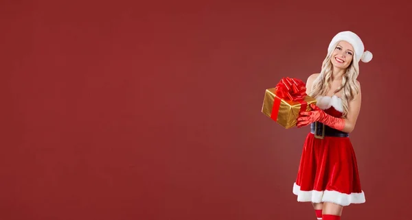 Menina em traje de Papai Noel com uma caixa de presente em mãos em um Christma vermelho — Fotografia de Stock