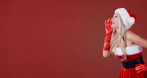 Uma menina em traje de Papai Noel grita em um backgro de Natal vermelho — Fotografia de Stock