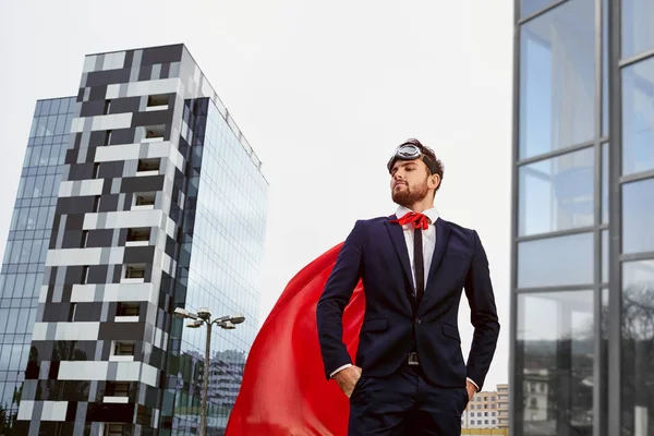 Um homem de negócios em um traje de super-herói está contra um edifício b — Fotografia de Stock