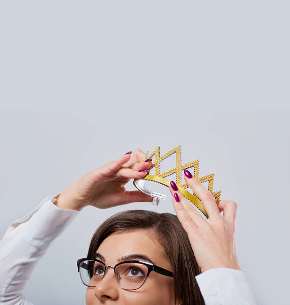 A businesswoman is holding a crown over his head