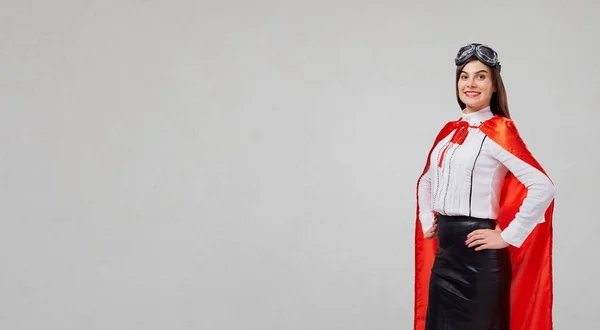 Mujer de negocios en un traje de superhéroe sobre un fondo gris . —  Fotos de Stock