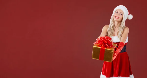 Una chica rubia en traje de Santas se ríe con un regalo en su han — Foto de Stock