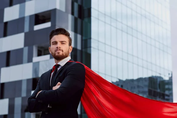 Empresário em um traje de super-herói contra um edifício de negócios b — Fotografia de Stock