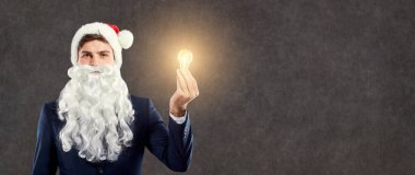 İşadamı Noel Baba elinde bir ampul ile.
