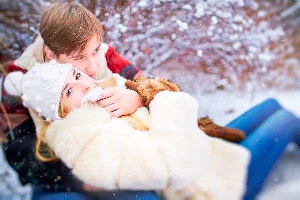 Um casal feliz está montando um trenó na neve em um parque na vitória — Fotografia de Stock