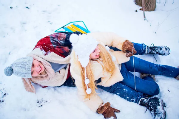 Um casal feliz está montando um trenó na neve em um parque na vitória — Fotografia de Stock