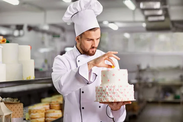 Chef pastelaria decora bolo na cozinha . — Fotografia de Stock