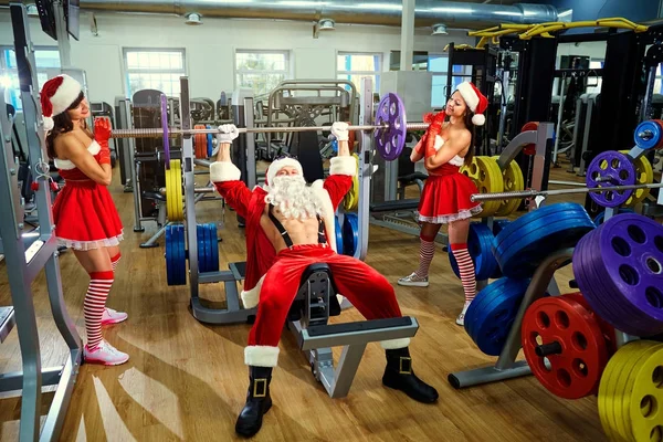 Sportowe Mikołaja z dziewczynami w Santas kostiumy w siłowni na — Zdjęcie stockowe