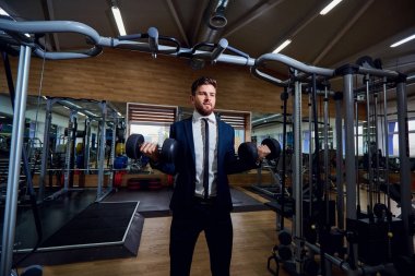 Spor salonunda dumbbells ile egzersizleri yapıyor işadamı